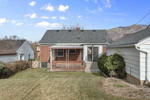 Back of house featuring central AC unit and a lawn