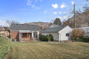 Rear view of property with central air condition unit, a mountain view, and a yard