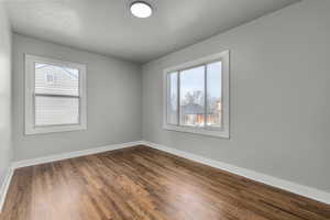 Unfurnished bedroom featuring a textured ceiling and dark hardwood / wood-style flooring