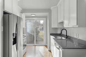 Kitchen featuring white cabinets, stainless steel appliances, light hardwood / wood-style floors, and sink