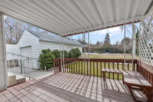 Wooden deck with a lawn, an outdoor structure, and a garage