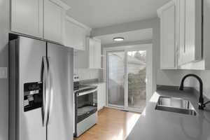 Kitchen featuring sink, white cabinetry, stainless steel appliances, and light hardwood / wood-style flooring