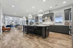 Kitchen with pendant lighting, a breakfast bar, a kitchen island, and light hardwood / wood-style flooring