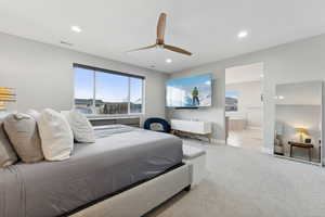 Carpeted bedroom featuring ceiling fan and ensuite bathroom