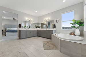 Bathroom featuring tile patterned floors, vanity, ceiling fan, and tiled tub