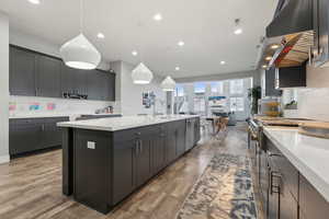 Kitchen with hardwood / wood-style floors, pendant lighting, a large island, and sink