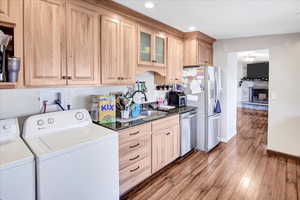 Interior space featuring sink, light brown cabinets, stainless steel appliances, separate washer and dryer, and wood-type flooring