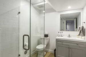 Bathroom with hardwood / wood-style floors, vanity, toilet, and walk in shower