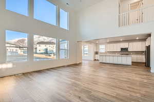 Unfurnished living room with a towering ceiling, a mountain view, and LVP flooring