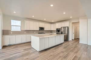 Kitchen featuring LVP flooring, stainless steel appliances, white cabinets, and sink