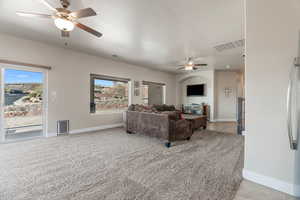 Living room featuring light carpet, a textured ceiling, and ceiling fan