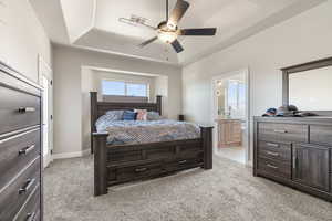 Carpeted bedroom featuring ensuite bathroom and ceiling fan