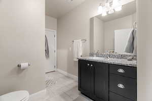 Bathroom featuring toilet, vanity, a chandelier, and tile patterned floors