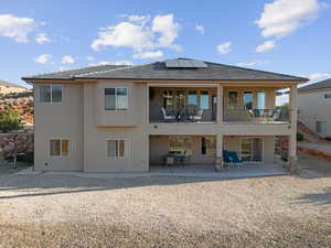 Back of house with solar panels and a patio area