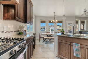 Kitchen featuring decorative backsplash, light stone counters, sink, and a chandelier