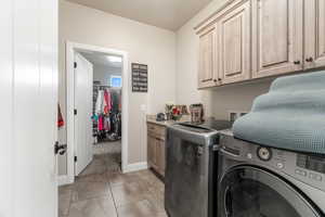 Laundry area featuring light tile patterned flooring, cabinets, and washing machine and clothes dryer