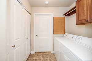 Laundry room featuring cabinets, light tile patterned floors, and washing machine and dryer