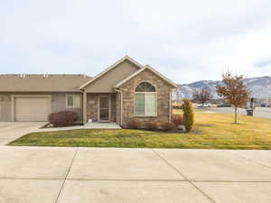 Ranch-style home with a mountain view, a garage, and a front lawn