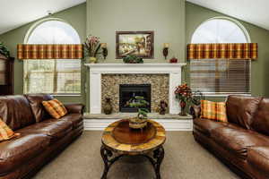 Living room with carpet flooring, a tile fireplace, and vaulted ceiling