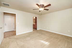 Unfurnished bedroom featuring ensuite bath, ceiling fan, and carpet floors