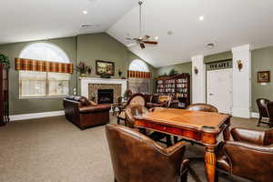 Carpeted dining room with a tile fireplace, vaulted ceiling, and ceiling fan