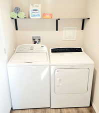 Clothes washing area featuring light hardwood / wood-style floors and washing machine and clothes dryer