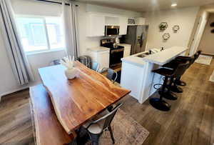 Dining space with sink and dark wood-type flooring