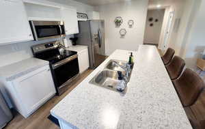 Kitchen with white cabinets, hardwood / wood-style flooring, and appliances with stainless steel finishes