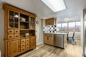 Kitchen featuring light stone countertops, tasteful backsplash, stainless steel dishwasher, a mountain view, and light hardwood / wood-style floors