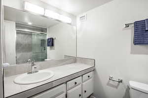 Bathroom with vanity, toilet, and an enclosed shower