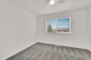 Carpeted spare room featuring ceiling fan