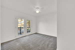 Carpeted empty room featuring ceiling fan and french doors