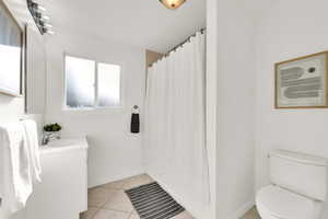 Bathroom with a shower with curtain, tile patterned flooring, vanity, and toilet