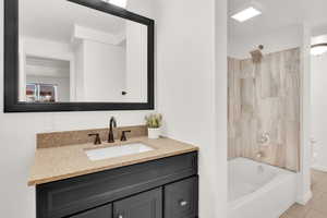 Full bathroom with tile patterned flooring, vanity, tiled shower / bath combo, and toilet