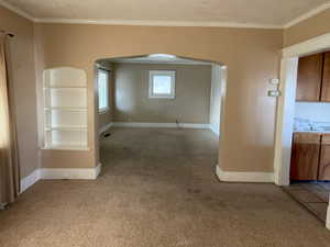 Unfurnished room featuring carpet, ornamental molding, and a textured ceiling