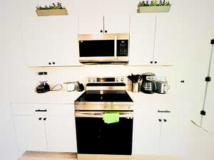 Kitchen featuring white cabinets and appliances with stainless steel finishes