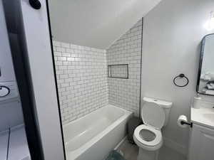 Full bathroom with vanity, a textured ceiling, toilet, tiled shower / bath, and lofted ceiling