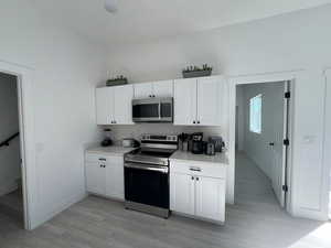 Kitchen featuring white cabinetry, stainless steel appliances, and light wood-type flooring