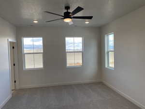 Owner's suite featuring ceiling fan, a healthy amount of sunlight, and a textured ceiling