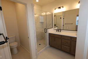 Bathroom with vanity, an enclosed shower, tile patterned floors, and toilet