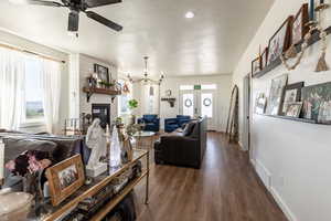 Living room with dark hardwood / wood-style floors, a large fireplace, ceiling fan with notable chandelier, and french doors