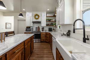 Kitchen with white cabinetry, sink, stainless steel appliances, dark hardwood / wood-style floors, and pendant lighting