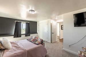 Bedroom with a textured ceiling, light carpet, and a closet