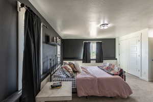 Carpeted bedroom featuring a textured ceiling and a closet