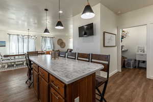 Kitchen with a center island, decorative light fixtures, dark hardwood / wood-style floors, and an inviting chandelier