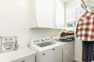 Laundry area featuring washer and clothes dryer, cabinets, and sink