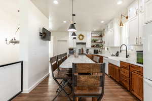 Kitchen with pendant lighting, a center island, white cabinets, sink, and dark hardwood / wood-style floors