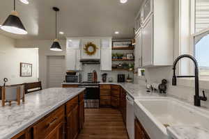 Kitchen featuring white cabinets, sink, decorative light fixtures, dark hardwood / wood-style flooring, and stainless steel appliances