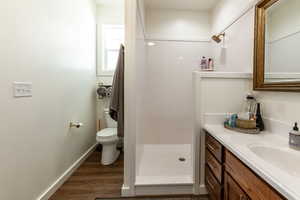 Bathroom with a shower, hardwood / wood-style floors, vanity, and toilet