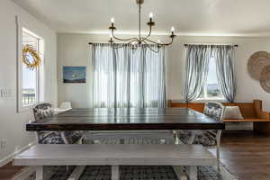 Dining room with dark wood-type flooring and a notable chandelier